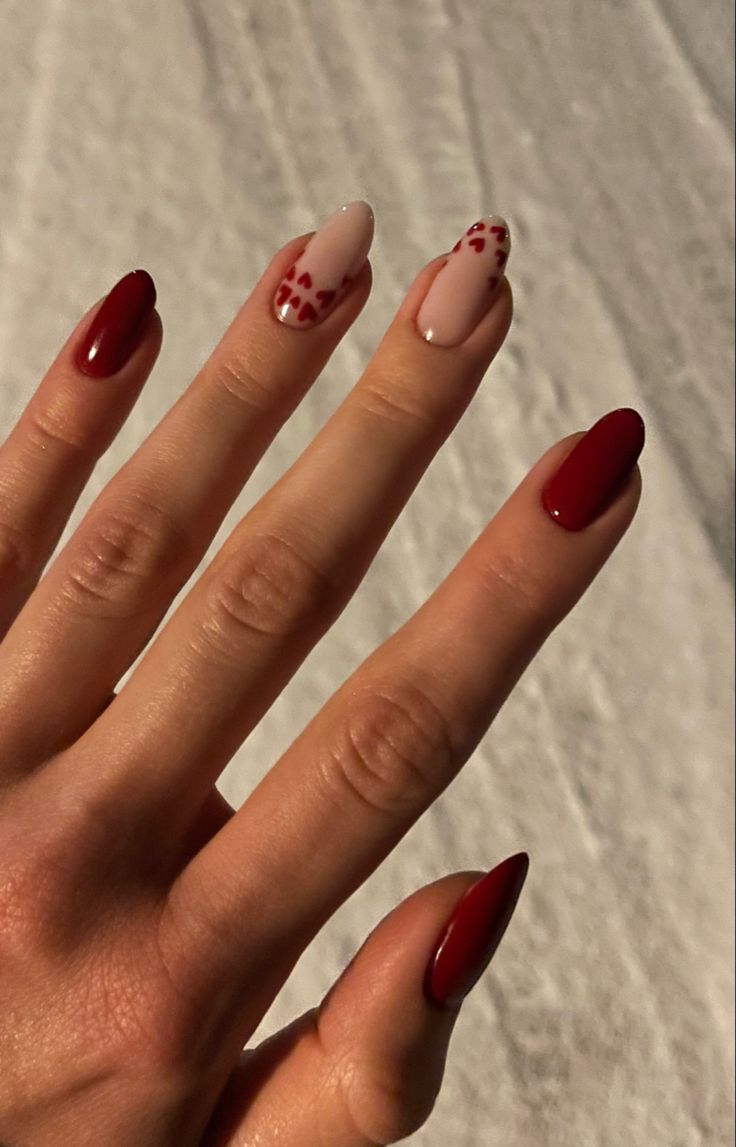 Chic Nail Design: Deep Red and Soft Nude with Playful Heart Patterns for Love and Celebration.