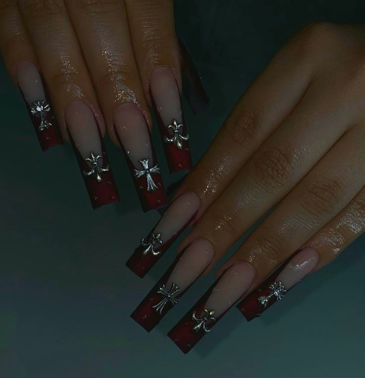 Chic Gradient Nail Design: Nude Base to Deep Red Tips with Glamorous Metallic Embellishments.