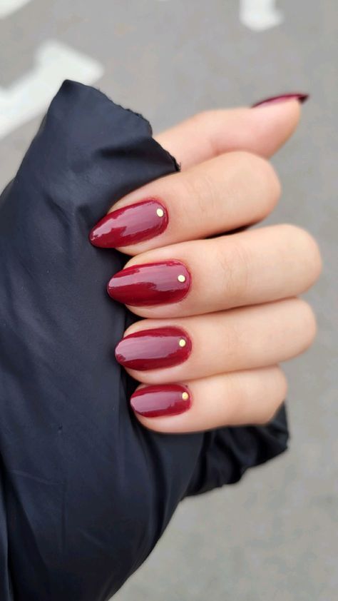 Sophisticated Glossy Red Almond Manicure with Subtle Gold Studs.