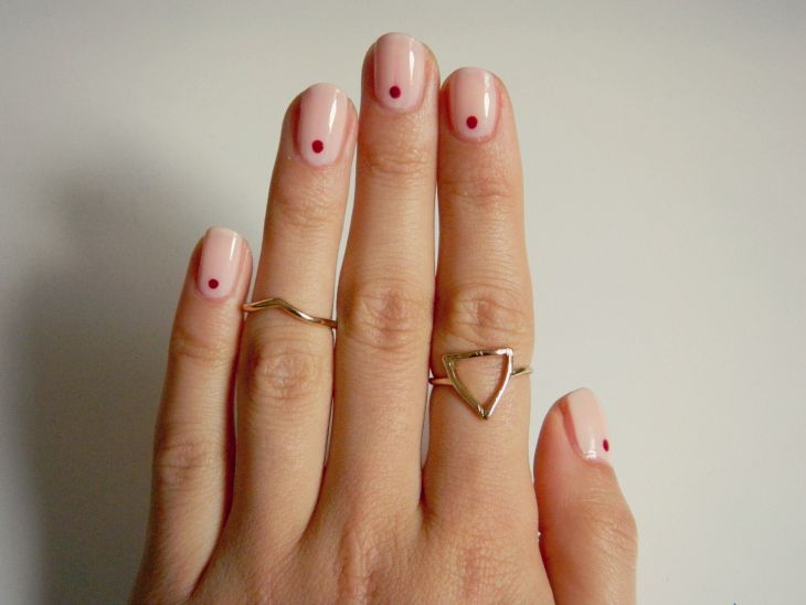 Chic Minimalist Nail Design: Elegant Nude Base with Stylish Red Dots and Complementary Rings.