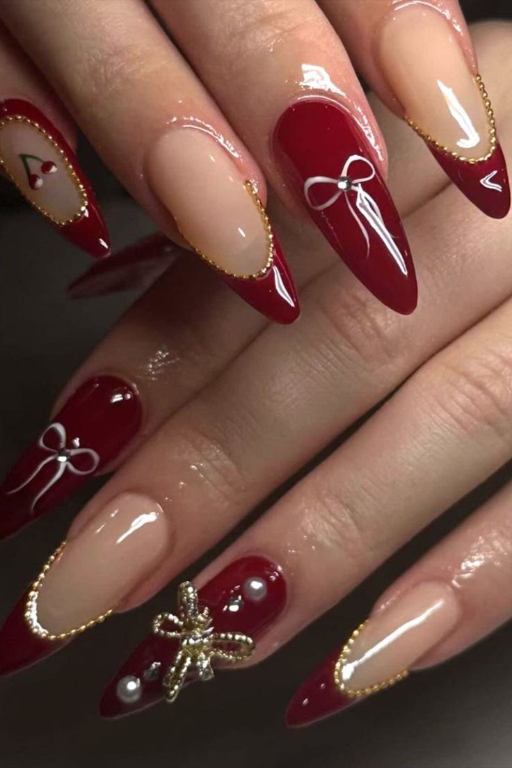 Sophisticated Almond-Shaped Nail Design with Deep Red and Nude Tones, Featuring Decorative Bows and Gold Accents.