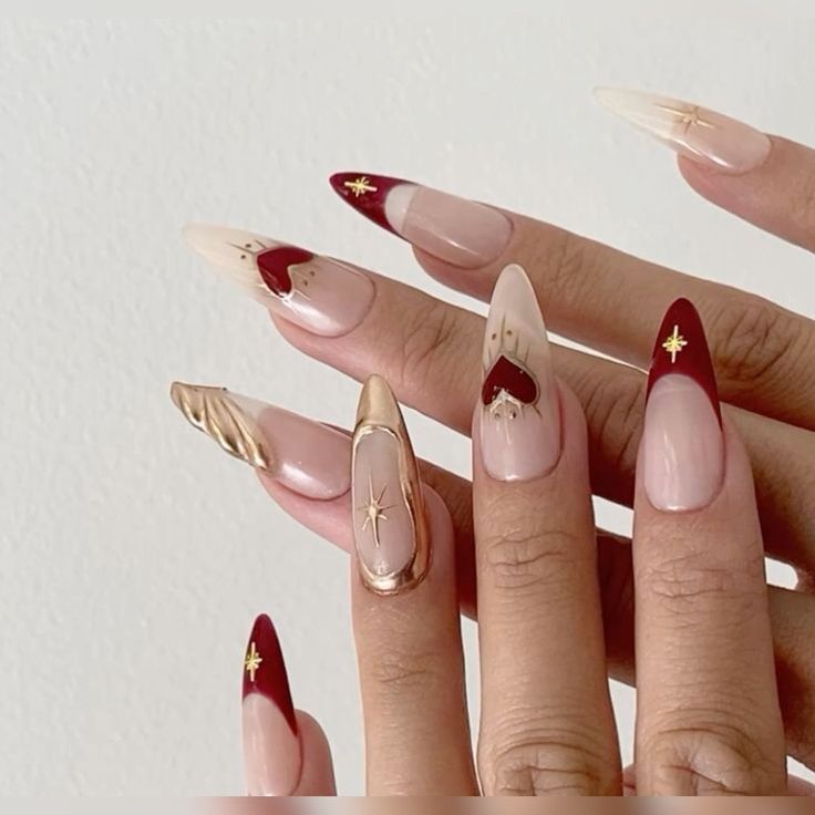 Sophisticated Nail Design: Nude and Deep Red with Gold Accents and Star Motifs.