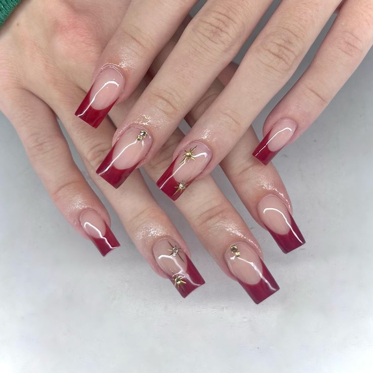 Sophisticated Red French Tip Nail Design with Glossy Finish and Golden Accents.