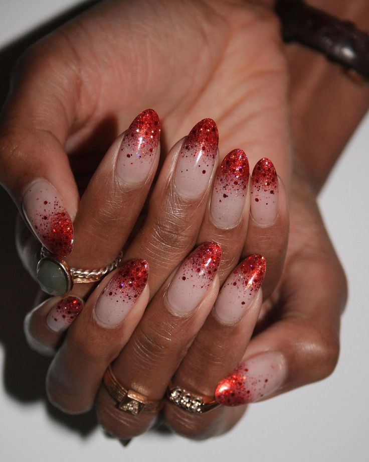 Glamorous Gradient Nail Design: Soft Nude to Vibrant Red with Glitter.