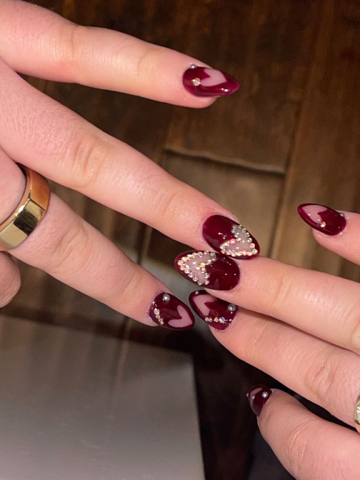 Chic Deep Burgundy Nail Design with Heart-Shaped Accents and Rhinestones for Special Occasions.