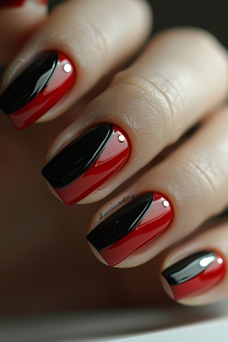 Bold Red and Black Geometric Nail Design with Glossy Finish and Elegant Accent Gems.