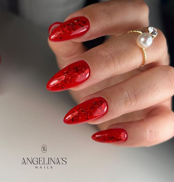 Chic Almond-Shaped Red Glitter Nails Enhanced by Elegant Gold and Pearl Ring.