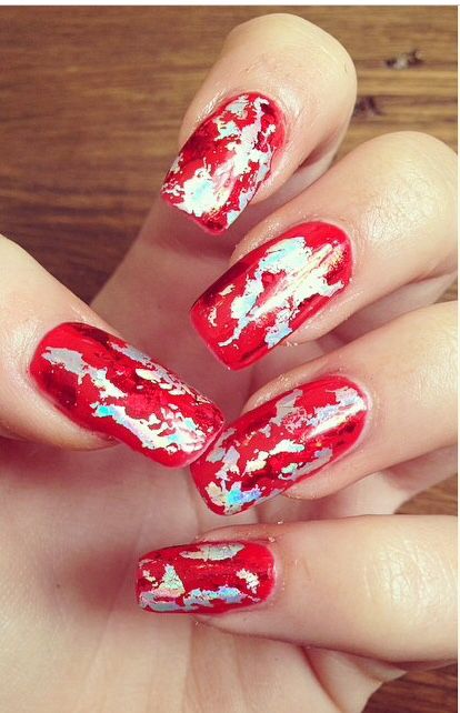 Bold Red Marbled Nails with Metallic Gold and Iridescent Accents for a Stunning Manicure Statement.