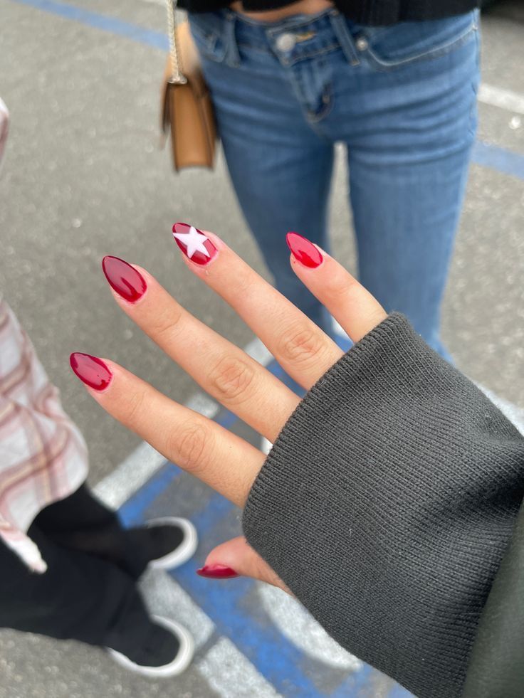 Elegant Red Nail Design with Accent Patterns and Star Detail