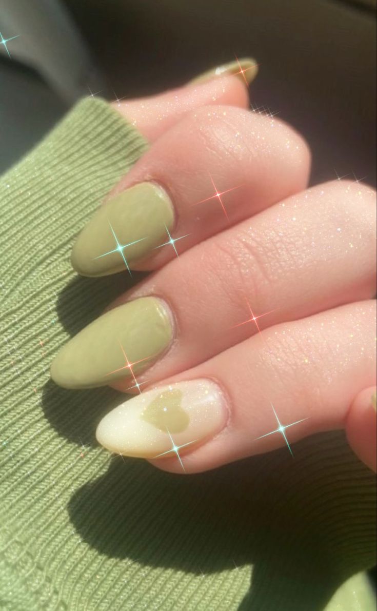 Chic Nail Design: Muted Green Elegance with a Playful Heart Accent.