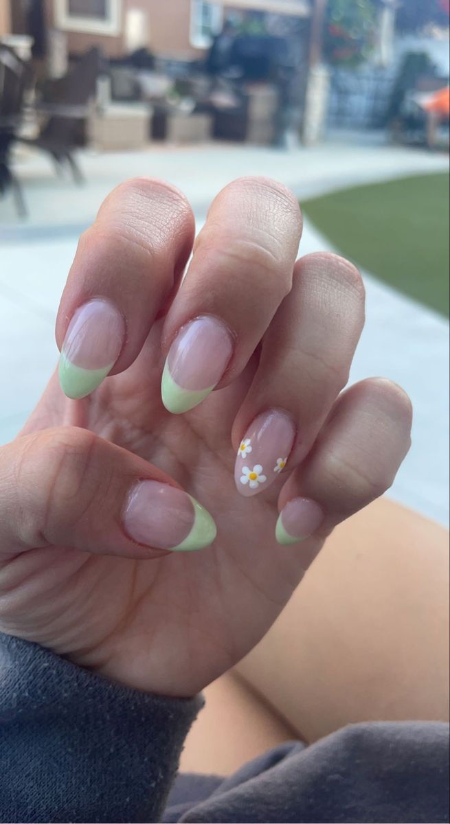 Elegant Soft Green French Tip Nails with White Daisy Accents for a Fresh Spring Look.