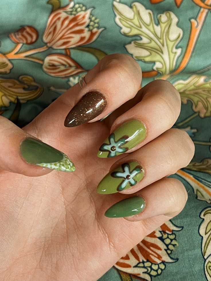 Eclectic Nail Design: Earthy Tones with Green Dominance, Floral Accents, and Textured Finishes.