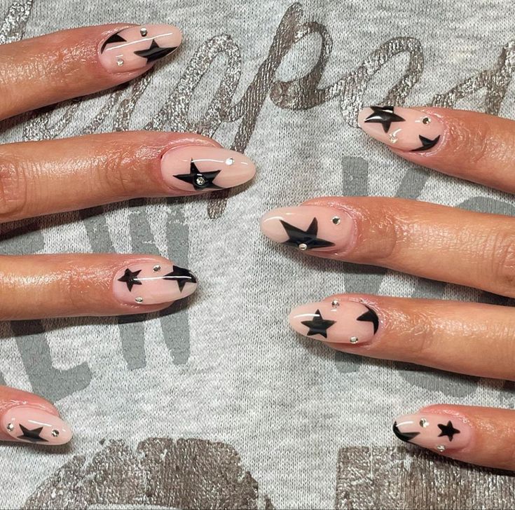 Chic Starry Nail Design: Nude Base with Bold Black Shapes and Glam Rhinestone Accents.