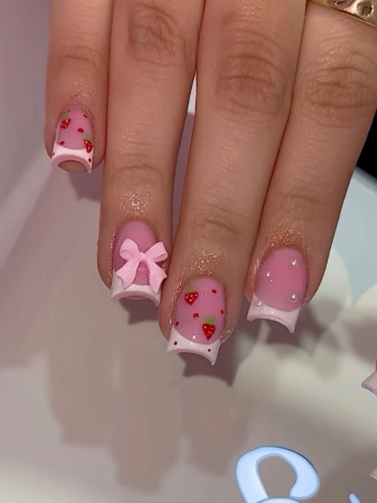 Whimsical Pastel Pink and White Nail Design with Strawberry Patterns and Glitter Accents.