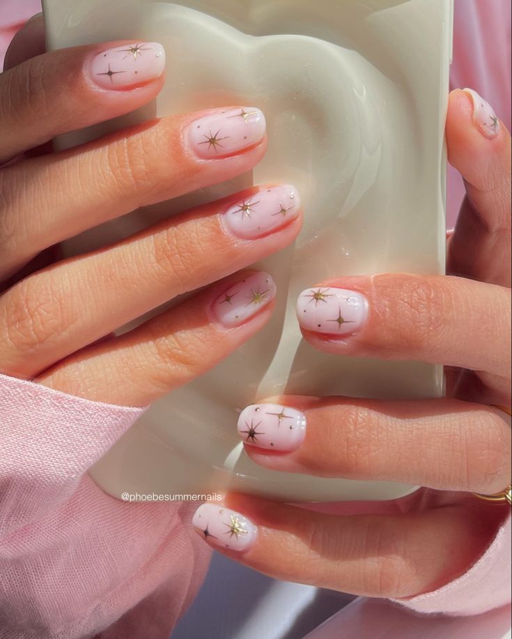 Whimsical Pink and White Gradient Nail Art with Gold Star Accents.