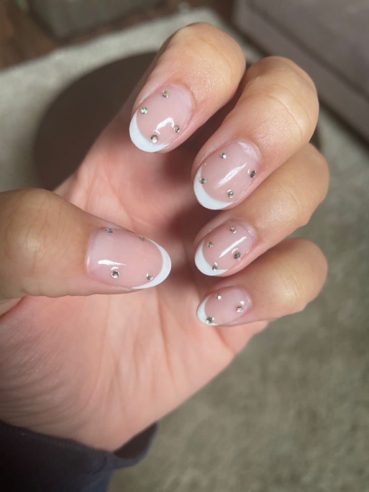 Sophisticated French Tip Nail Design with Subtle Embellishments and a Soft Nude Base.