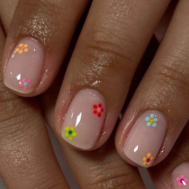 Playful Spring-Inspired Floral Nail Design with Sheer Pink Base and Colorful Decals.