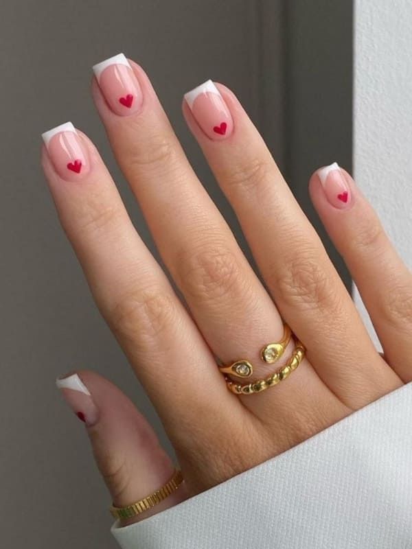 Delicate French Manicure with Playful Hearts and Elegant Gold Accents.