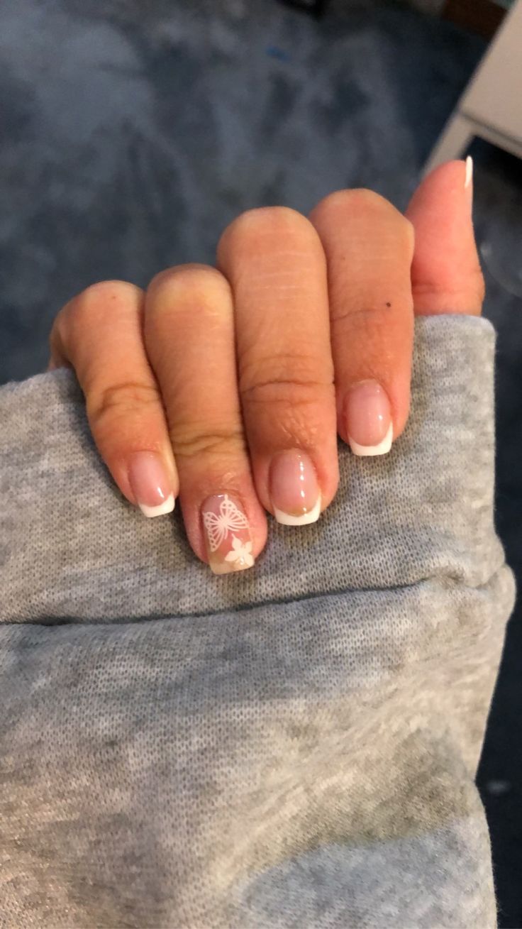 Elegant Nude French Tip Nail Design with Floral Butterfly Accent.