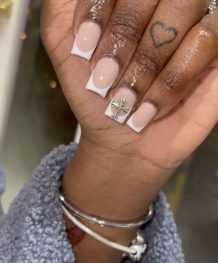 Chic French Tip Manicure with Nude Base and Silver Cross Embellishment