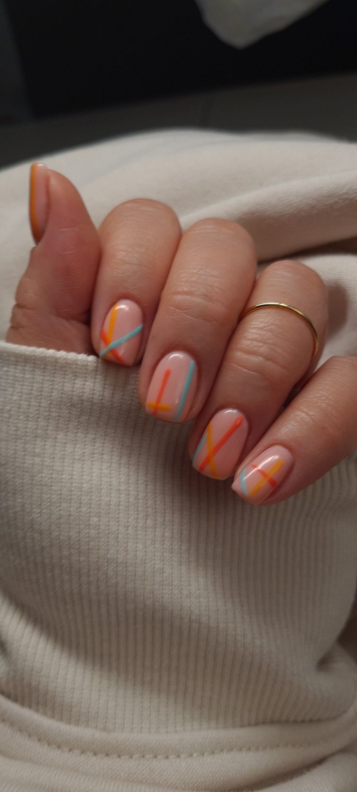 Chic Summer Nail Art: Soft Peach Base with Bold Diagonal Stripes in Orange, Aqua, and Pastel Yellow.