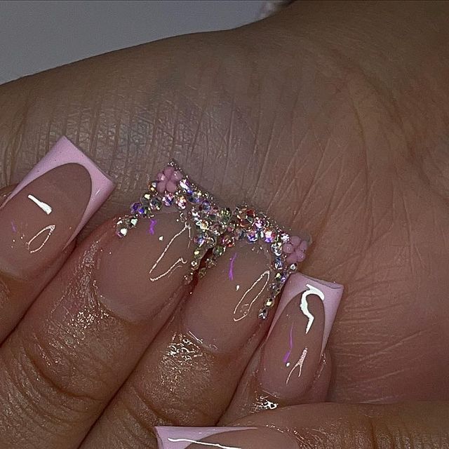 Elegant Pink French Tip Nail Design Adorned with Glamorous Sparkly Embellishments.