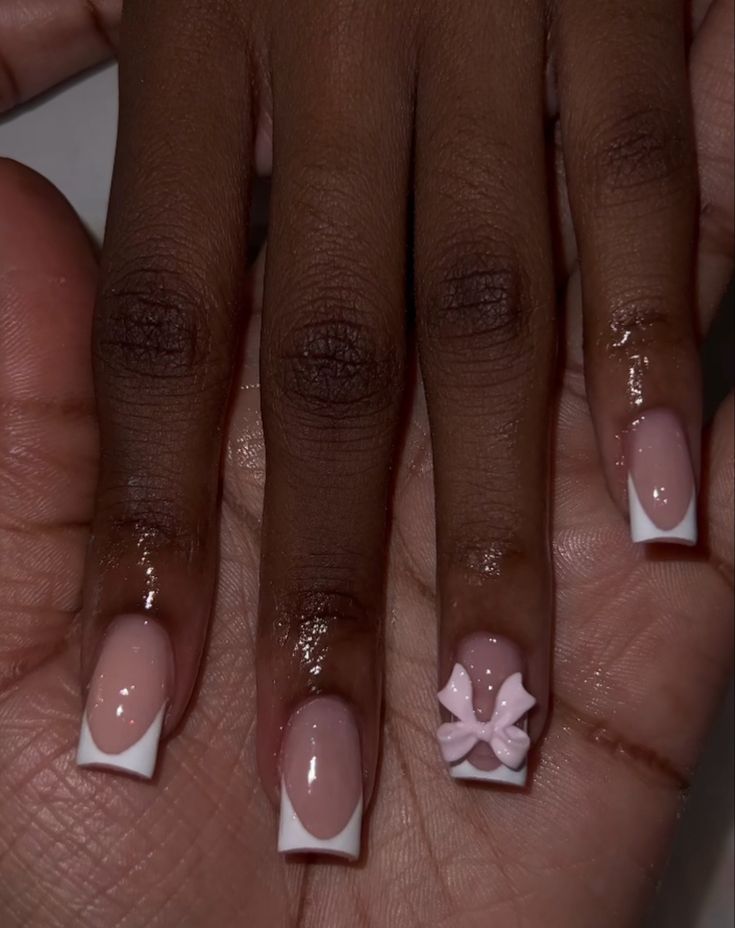 Sophisticated Soft Pink and White French Tip Nail Design with Whimsical Bow Accent.