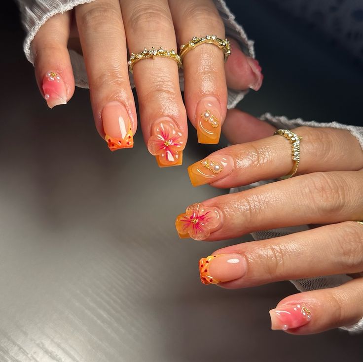 Vibrant Pink and Orange Floral Nail Design with Sparkling Embellishments.