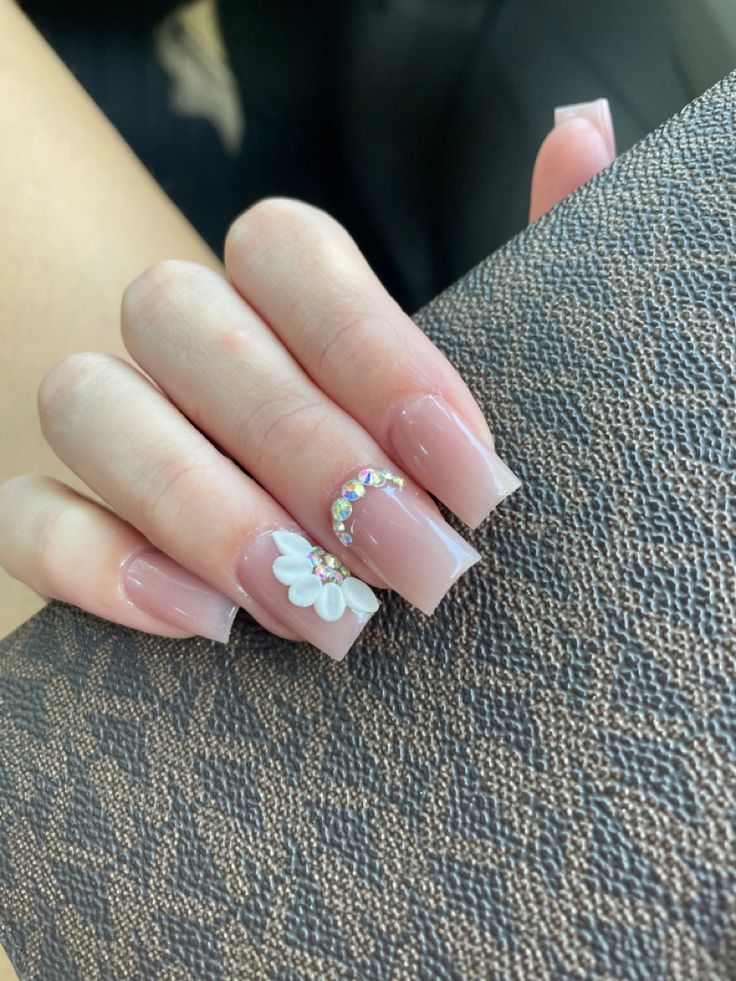 Sophisticated Nude Nail Design with White Flower Accent and Rhinestone Detail