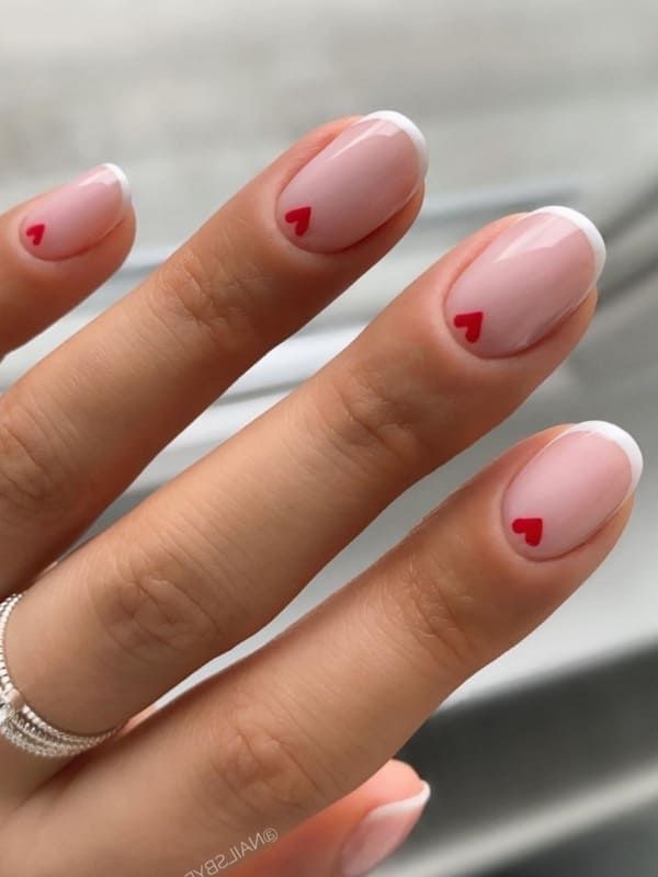 Chic Nude Nail Design Accented with Playful Red Heart Tips.