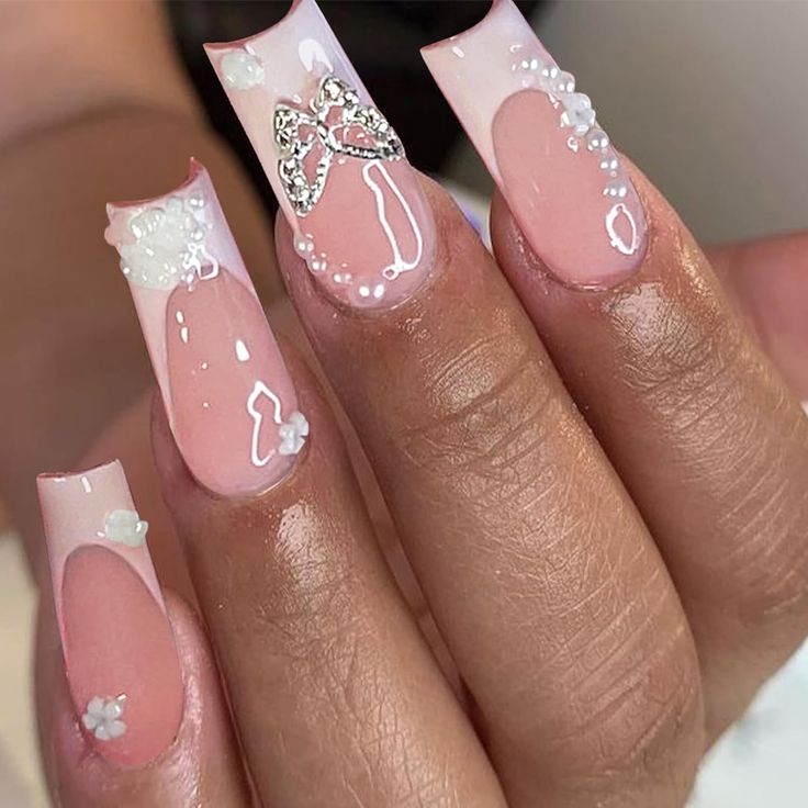 Chic Soft Pink Nail Design with Intricate White Accents and Floral Embellishments.