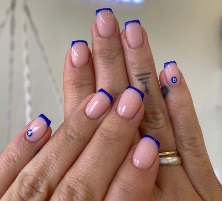 Stylish Nude and Blue Tip Nail Design with Unique Eye Motifs