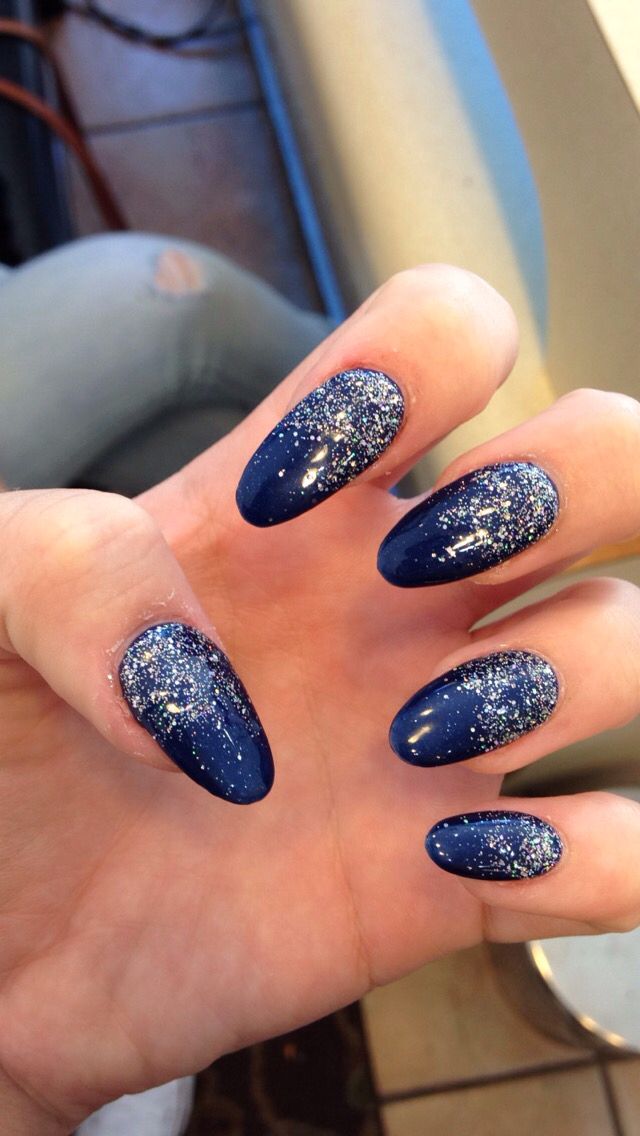 Glamorous Navy Blue Almond Nails with Glossy Finish and Glitter Accents.