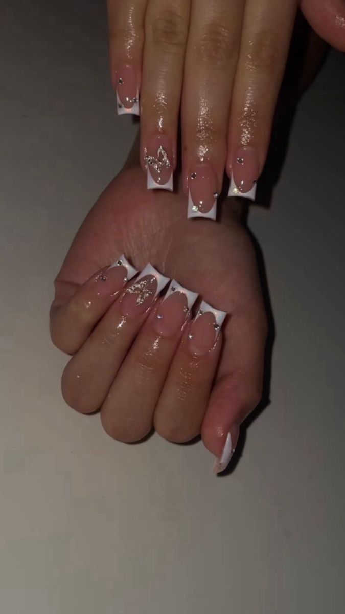 Elegant French Tip Nail Design with Gold Accents and Gem Embellishments.