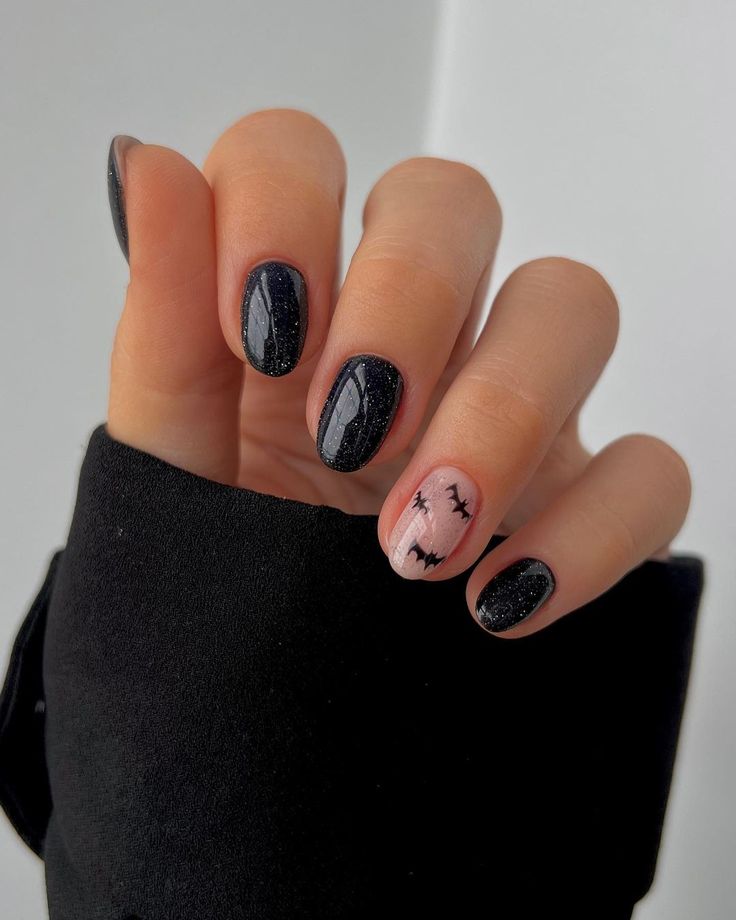 Striking Elegant Nail Design: Glossy Black and Soft Pink with Sparkly Accents and Edgy Graphics.