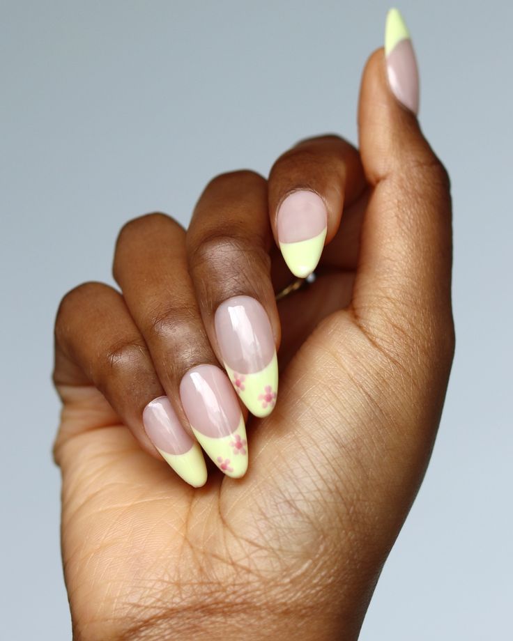 Elegant Spring-Summer Nail Design: Soft Nude Base with Pastel Yellow Tips and Floral Accents.