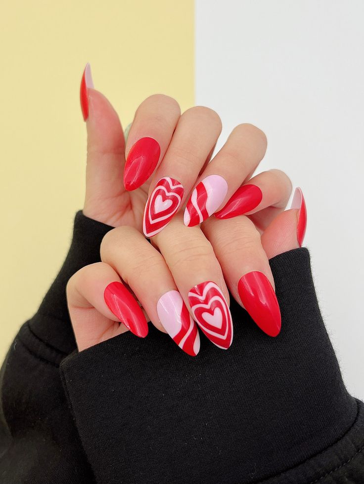 Romantic Almond-Shaped Nail Design with Bold Red and Pink Heart Motifs for Valentine's Day.