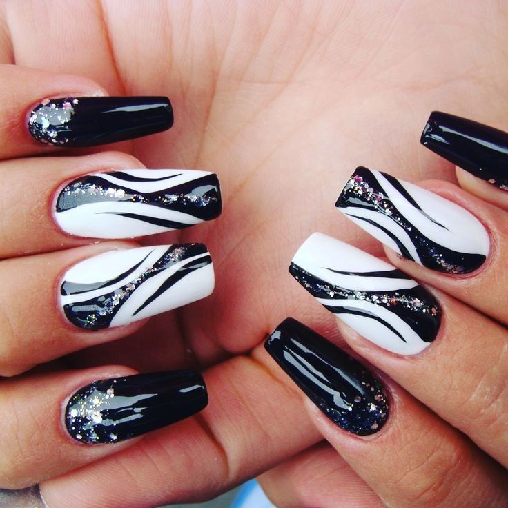 Bold Glamorous Nail Design: Glossy Black and White with Sparkling Glitter Accents.