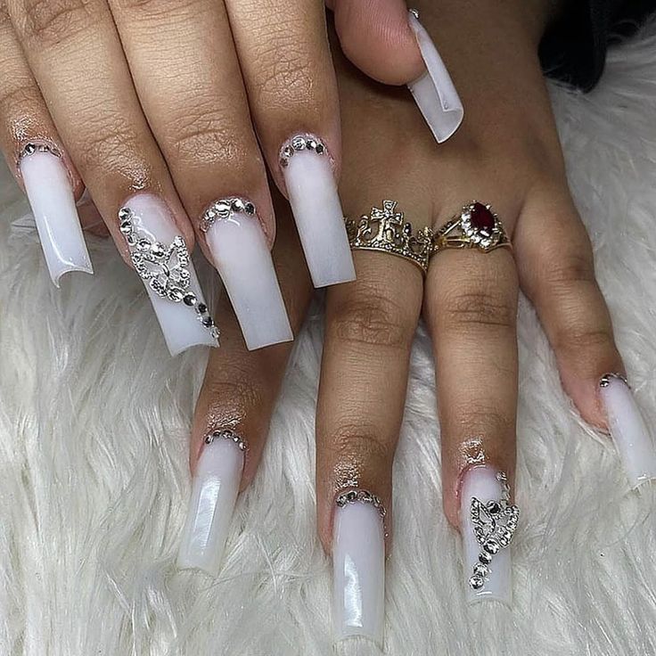 Chic Long Clear Tip Nail Design with Intricate Embellishments for Glamorous Occasions.