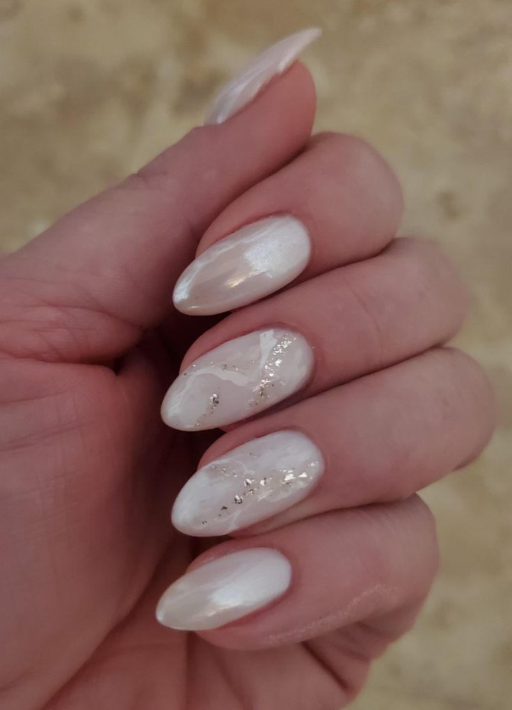 Sophisticated Soft White Nail Design with Iridescent Finishes and Delicate Metallic Accents.