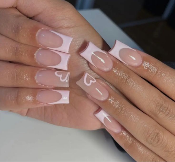 Chic and Playful Soft Pink French Tip Nail Design with Heart Accents.