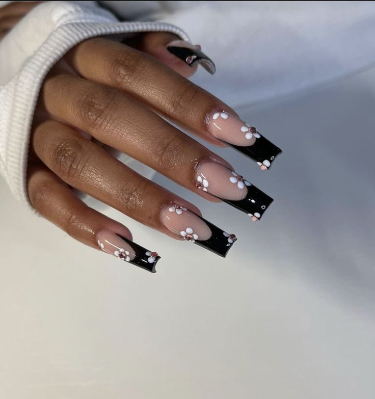 Sophisticated Nude and Glossy Black Nail Design with Delicate White Floral Accents.