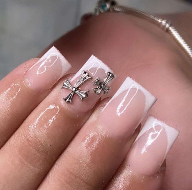 Chic French Manicure with Metallic Cross Accents for a Modern Twist.