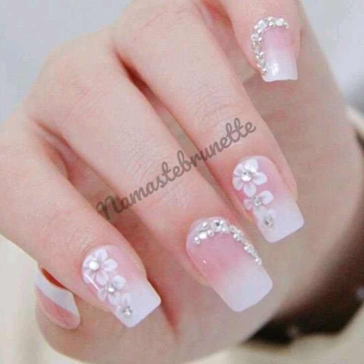 Elegant French Manicure with Soft Pink Tips, Floral Designs, and Sparkling Rhinestones.