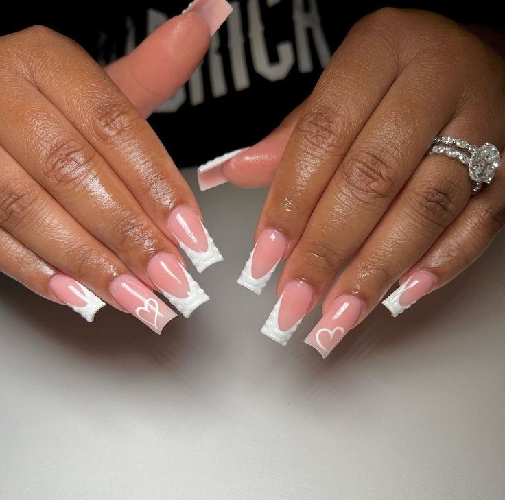 Chic Freestyle Nail Design: Soft Pink Base with Bold White French Tips and Playful Heart Patterns.