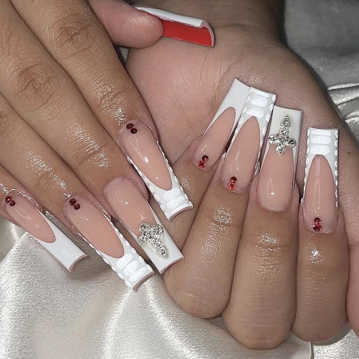 Elegant Nail Design: Elongated Squared Tips in Glossy White and Nude with Red Gems and Silver Charms.