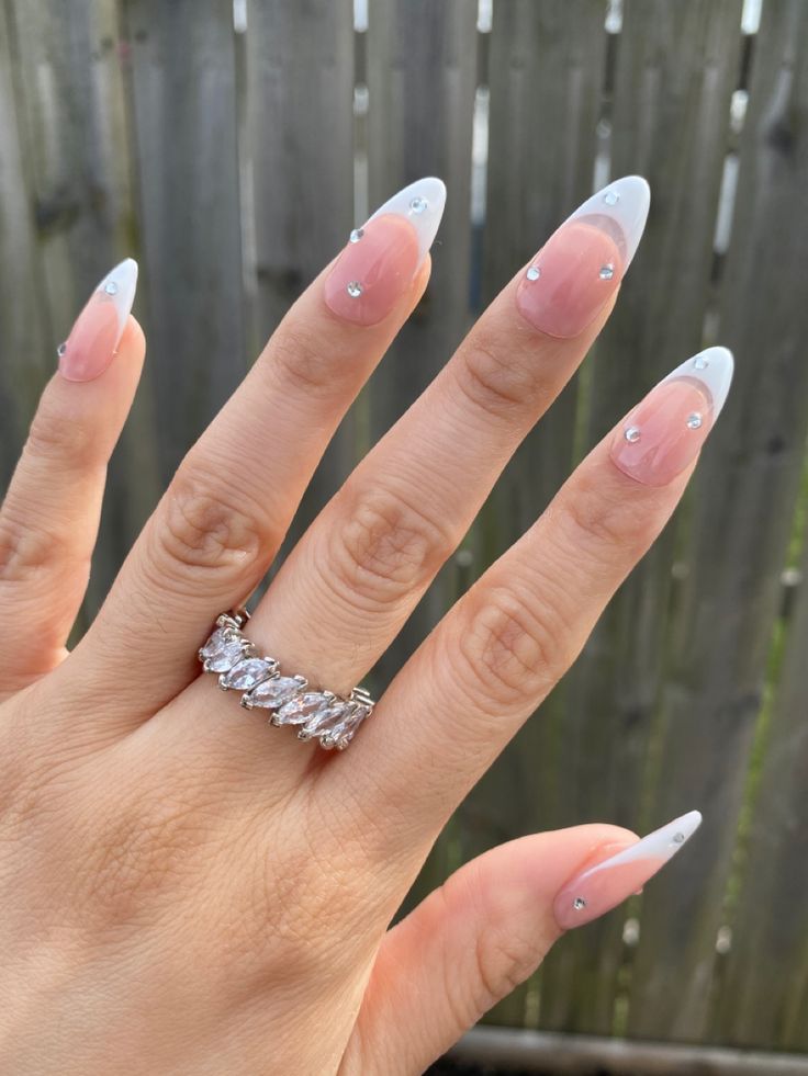 Sophisticated Long-Tipped French Manicure with Sparkling Rhinestones and Elegant Ring.