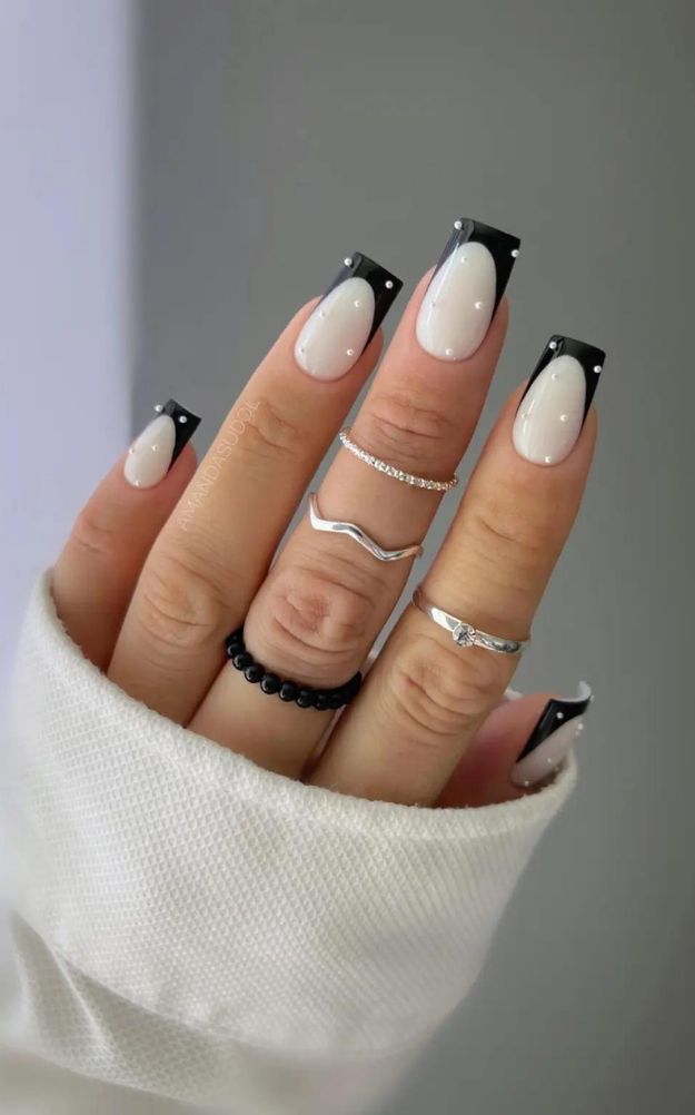 Sophisticated French Tip Nail Design with Striking Black Accents and Elegant Silver Accessories.