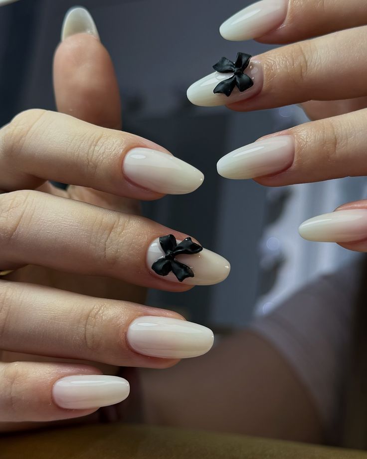 Sophisticated Almond-Shaped Ombre Nails with Playful Black Bow Accents.