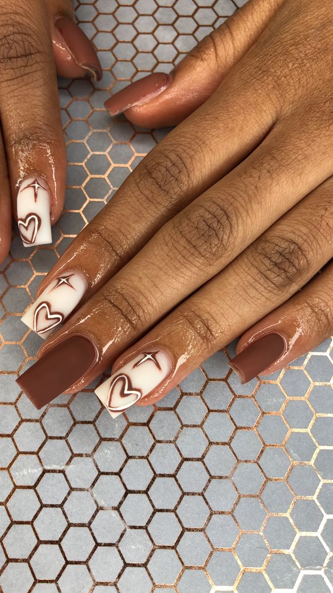 Elegant Brown and Cream Nail Design with Intricate Heart and Arrow Patterns.